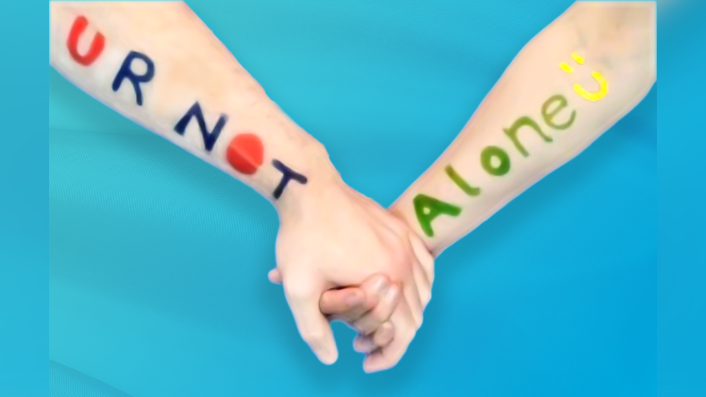 Close-up picture of the arms of two people holding hands with U R Not Alone written in pen on their arms to help people affected by someone else's drinking know they are not alone 
