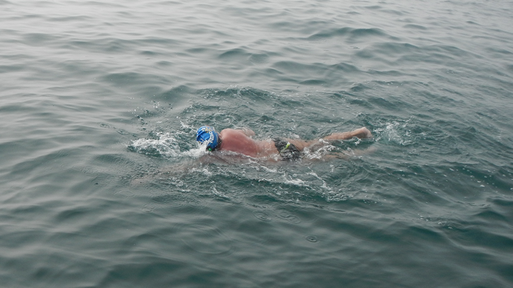 Man swimming English Channel in blue Nacoa swim cap raising money for children of alcoholics