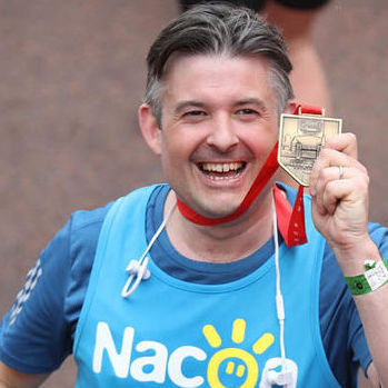 Nacoa patron Jonathan Ashworth holding London marathon medal helping children of alcoholics