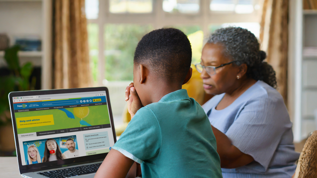 Grandmother sitting at laptop with grandson looking at Nacoa website - helping grandchildren affected by their parent's drinking
