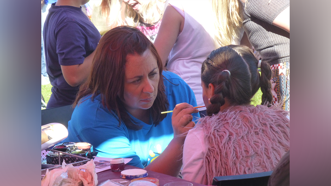Volunteer face painting child's face at Upfest to raise money for children of alcoholics