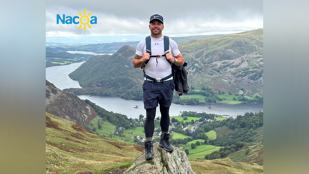Dean standing on rock with river and hills in background during his three peaks challenge shared for his blog "Climbing – for a cause and why I chose Nacoa"