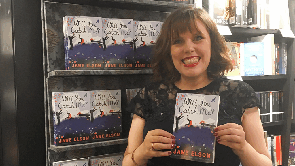 Jane Elson stood against a backdrop of many copies of her book Will You Catch Me?